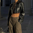 Schwarze Kunstlederjacke, kurz geschnitten, mit Umlegekragen und Knopfdetails. Perfekt für Y2K-Mode, Grunge-Streetstyle und Herbsttrends.