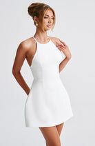 Weißes, ärmelloses Minikleid mit Neckholder-Design, ideal für Sommermode und elegante Anlässe. Perfekt für stilvolle, moderne Frauen.