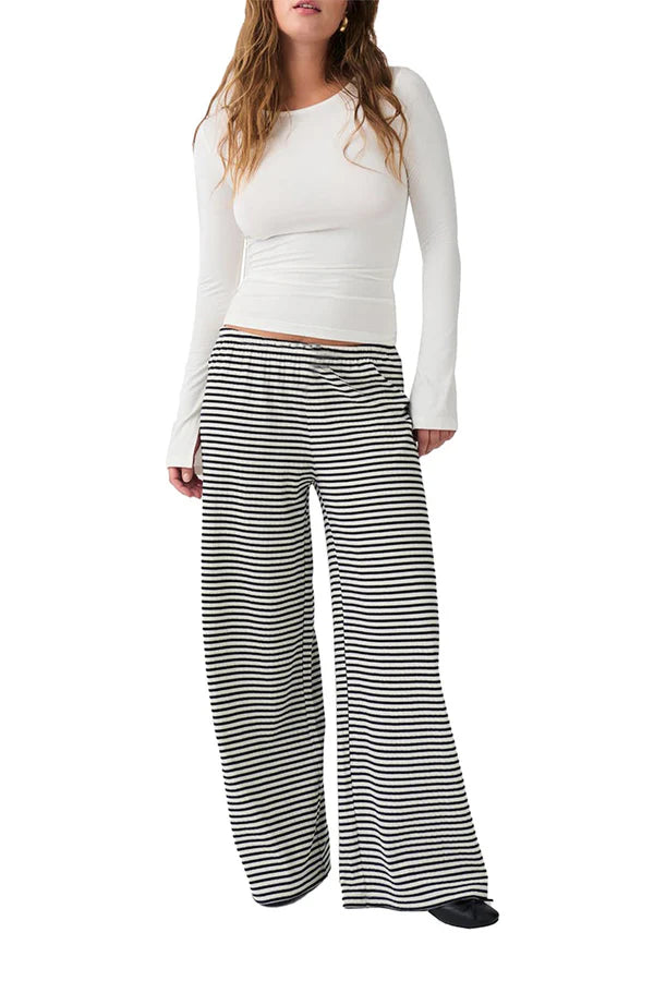 Damenmode: Weißes Langarmshirt und schwarz-weiß gestreifte, weite Hose. Bequem, stilvoll, ideal für Freizeit und Alltag.