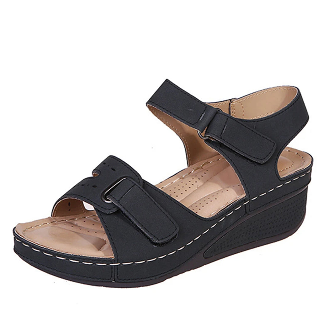 Schwarze Damen-Sandale mit Klettverschluss, bequemer Keilabsatz, ideal für Sommermode. Perfekt für Alltag und Freizeit.