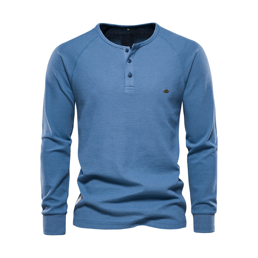 Blaues Herren-Henley-Shirt aus Baumwolle, langärmelig, mit Knopfleiste. Ideal für Freizeitmode, bequem und stilvoll. Perfekt für Herbst und Winter.