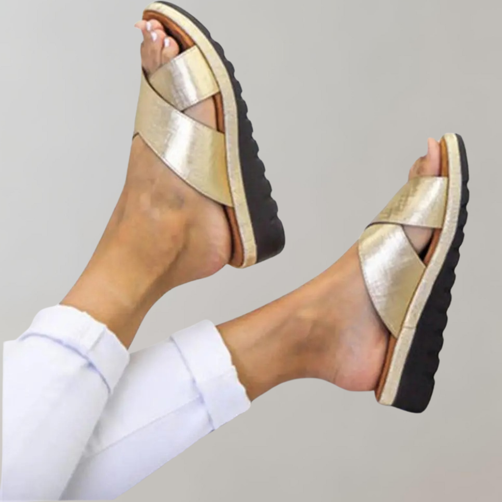 Goldene Sandalen mit Kreuzriemen, bequemer schwarzer Sohle und modernem Design. Perfekt für Sommermode und lässige Outfits.