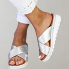 Silberne Damen-Sandalen mit Kreuzriemen und weißer Sohle, ideal für Sommermode. Bequeme, stilvolle Schuhe für Freizeit und Alltag.