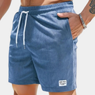 Blaue Herren-Badeshorts mit Kordelzug, geripptem Stoff und Taschen. Ideal für Sommer, Strand und Schwimmen. Modisch und bequem.