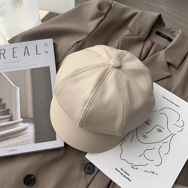 Beige Leder-Newsboy-Cap auf braunem Mantel, stilvoll und modern. Perfekt für Herbst und Winter. Trendige Damenmode, koreanischer Stil.