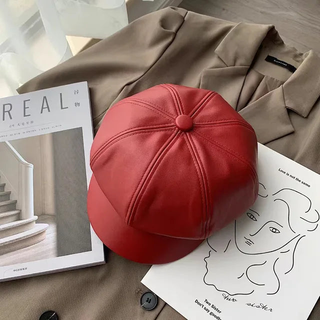 Rote Leder-Newsboy-Mütze auf braunem Mantel, stilvoll und modern. Perfekt für Herbst- und Wintermode. Hochwertige PU-Lederkappe, koreanisches Design.