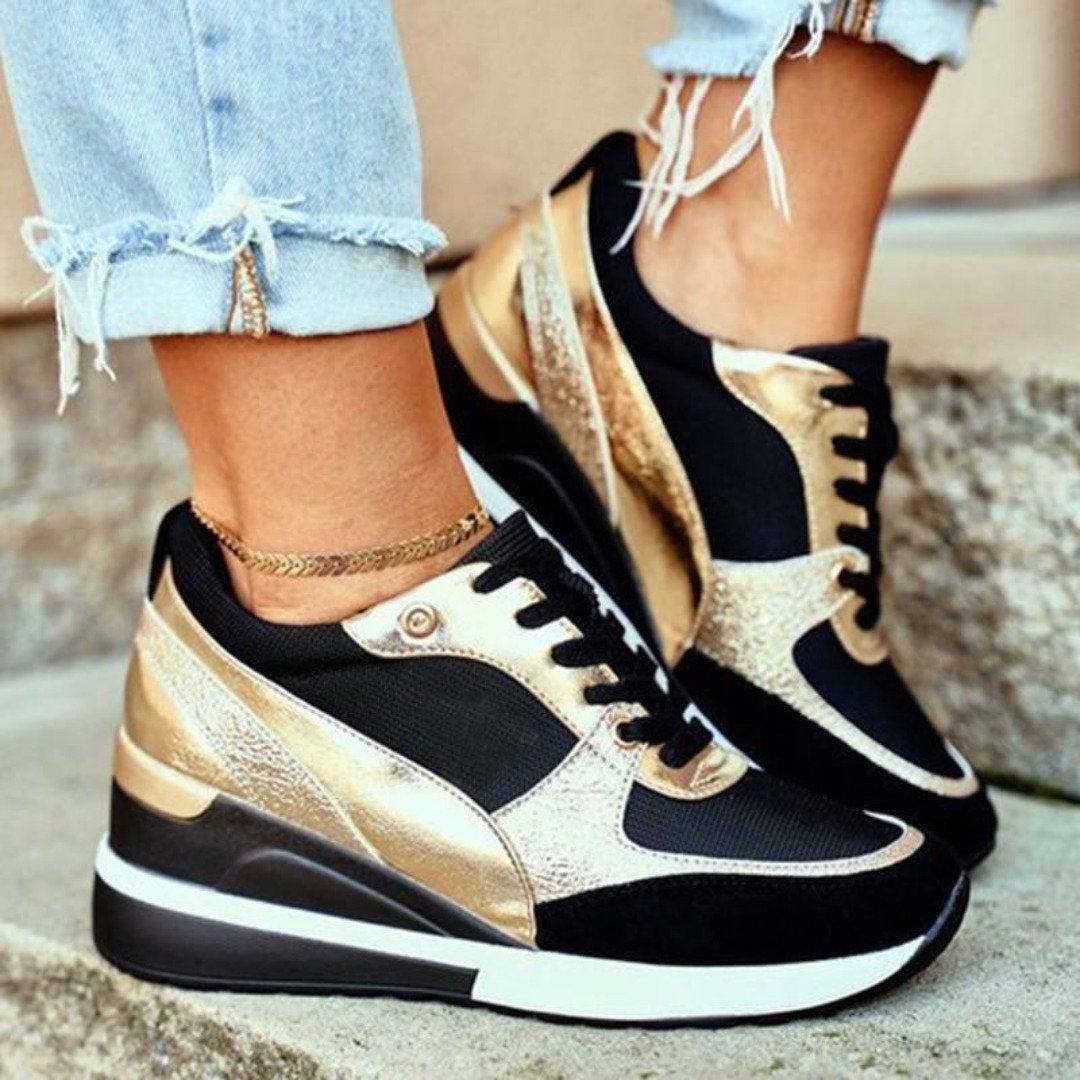 Stylische Damen-Sneaker in Schwarz und Gold, kombiniert mit zerrissenen Jeans. Perfekt für trendige Freizeitlooks und modische Outfits.