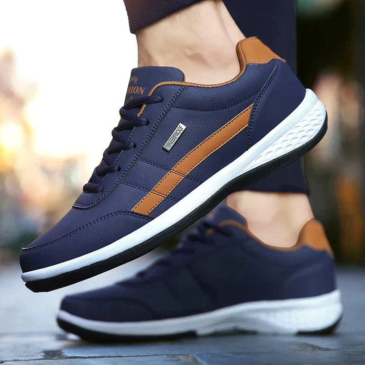 Dunkelblaue Sneaker mit braunen Akzenten, ideal für Herren. Bequeme Sportschuhe mit weißer Sohle, perfekt für Freizeit und Sport.