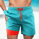 Herren-Badeshorts türkis mit geometrischem Muster und orangefarbenem Akzent am Strand.