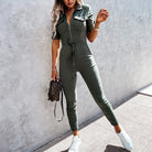 Damen Jumpsuit in Olivgrün, tailliert mit Reißverschluss und Kordelzug, kombiniert mit weißen Sneakers und kleiner Handtasche.