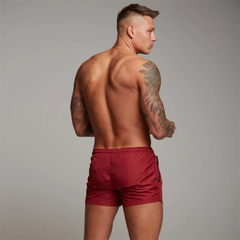 Herren-Badeshorts in Rot, schnell trocknend, mit Reißverschlusstaschen und Mesh-Futter. Ideal für Sommer, Strand und Sport.