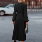 Elegantes schwarzes Maxikleid mit langen Ärmeln, kombiniert mit einer stilvollen Krokodilleder-Handtasche. Perfekt für Abendveranstaltungen.