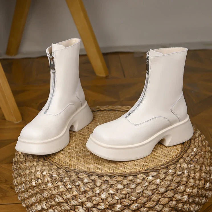 Weiße Stiefeletten mit Reißverschluss, klobiger Sohle und modernem Design auf geflochtener Unterlage. Trendige Damenmode, stilvolle Schuhe.
