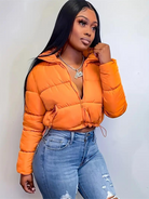 Frau in orangefarbener Steppjacke und zerrissenen Jeans. Modetrend, Winterjacke, Damenmode, Streetstyle, lässiger Look, stilvoll.