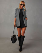 Eleganter Damenblazer in Schwarz-Grau, kombiniert mit schwarzem Kleid und Stiefeln. Perfekt für stilvolle Herbstmode. Hochwertige Materialien.