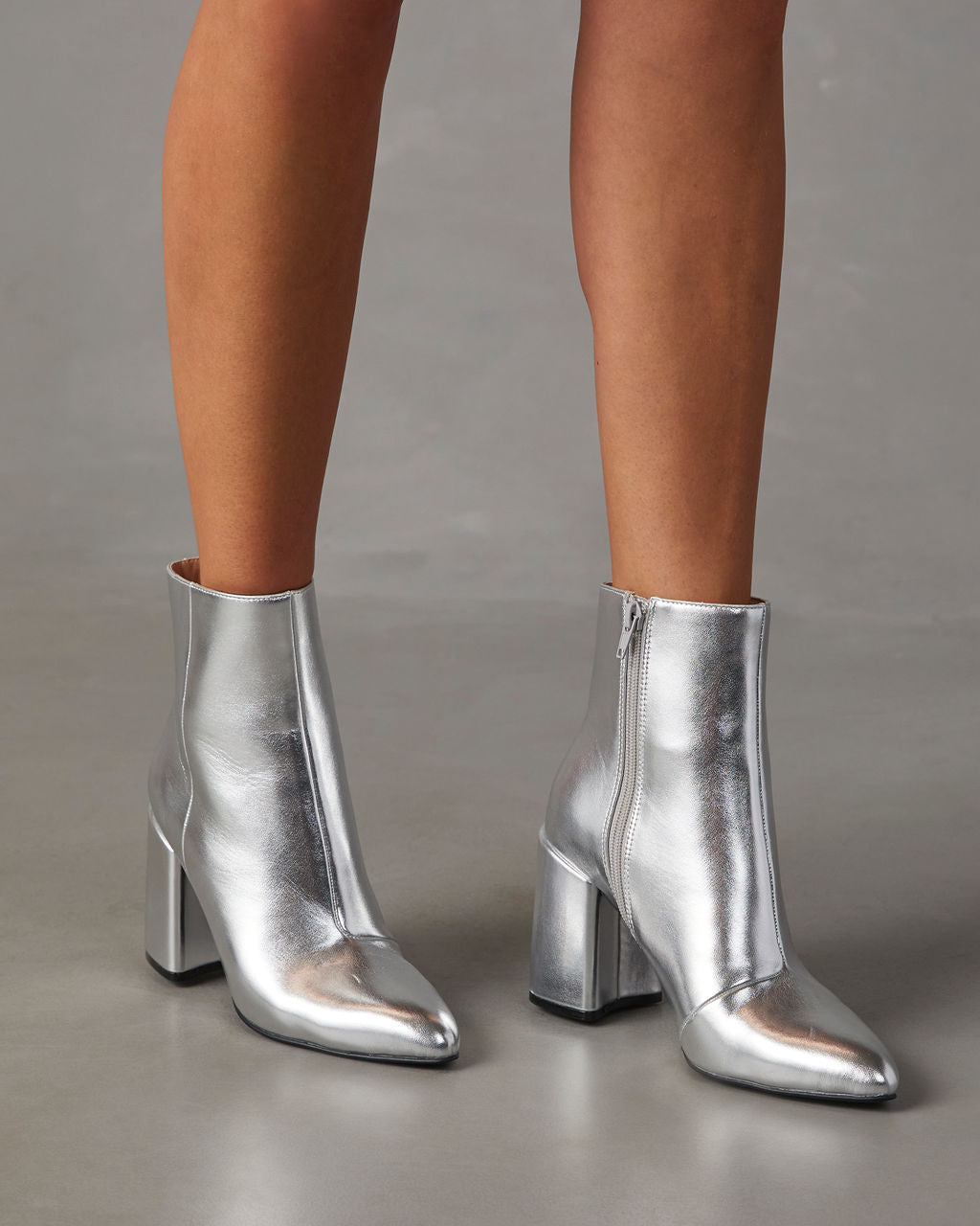 Silberne Damenstiefeletten mit Blockabsatz, Reißverschluss und spitzer Zehenpartie. Modische Schuhe für Herbst/Winter, ideal für trendige Outfits.