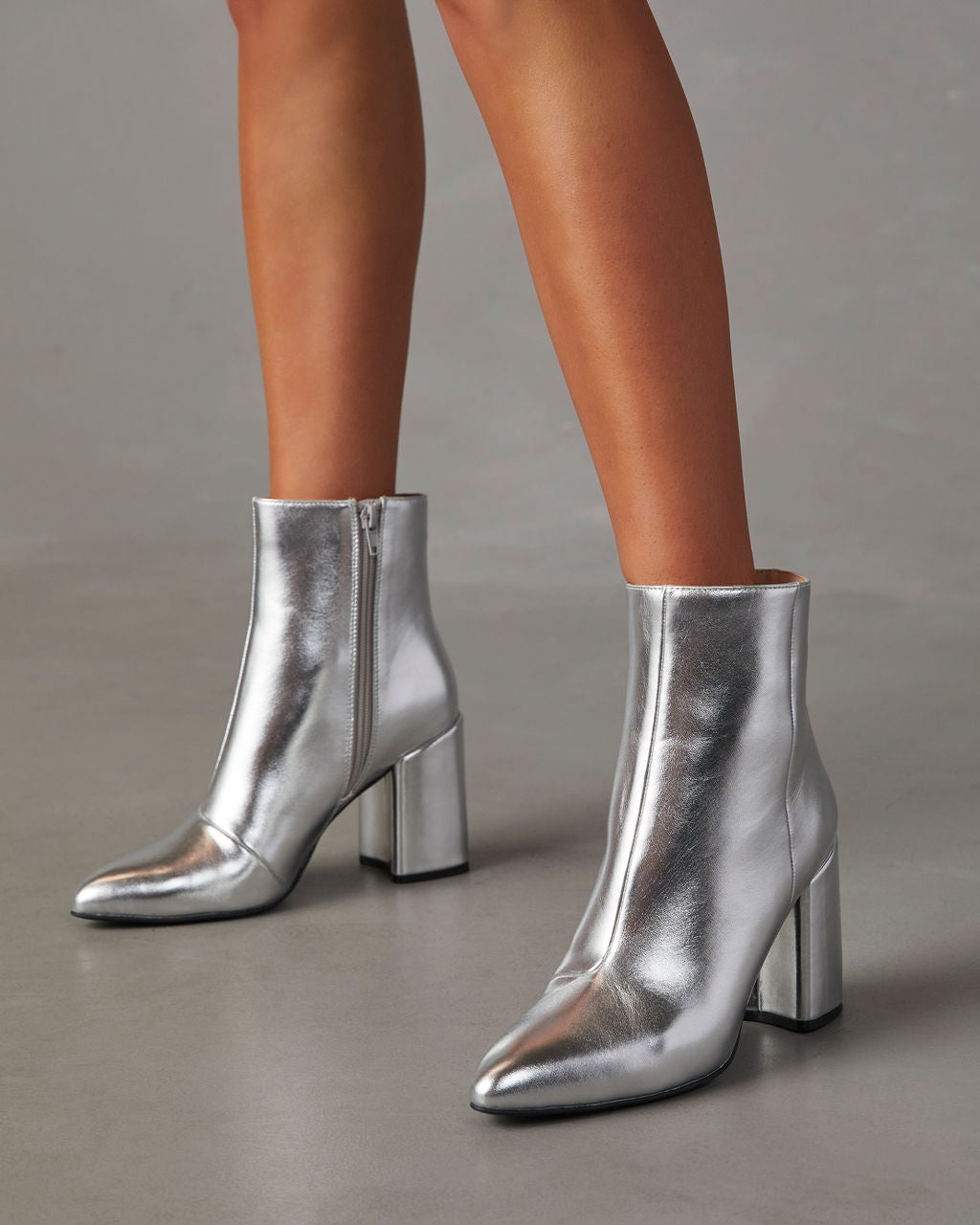 Silberne Damenstiefeletten mit Blockabsatz, glänzendem Finish und seitlichem Reißverschluss. Perfekt für modische Outfits und elegante Anlässe.