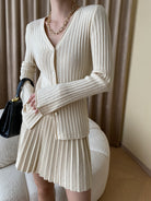 Damenmode: Eleganter cremefarbener Strick-Cardigan mit V-Ausschnitt und Faltenrock. Perfekt für stilvolle Herbst- und Winteroutfits.