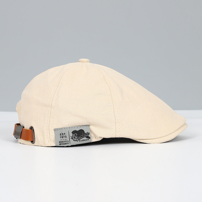 Beige Schiebermütze aus Baumwolle mit verstellbarem Lederriemen, stilvollem Design und hochwertigem Etikett, ideal für modische Outfits.