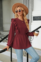 Elegante Frau in roter Bluse mit Rüschen, Sonnenbrille und Hut, hält Kaffee. Modetrend, Damenmode, Herbstoutfit, stilvolle Freizeitkleidung.
