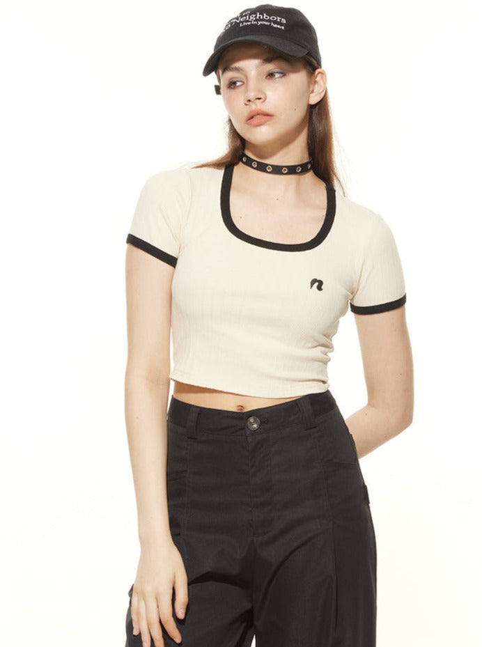 Frau in modischem Crop-Top und schwarzer Hose, trägt eine Baseballkappe und Choker. Trendige Streetwear, lässiger Look, urbaner Stil.