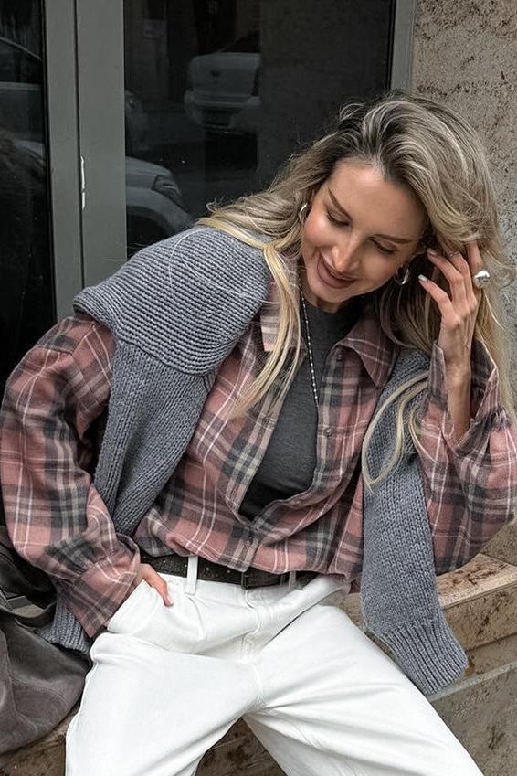 Frau in modischem Herbst-Outfit: karierte Bluse, grauer Pullover, weiße Hose. Trendige Damenmode, lässiger Look, Streetstyle, Herbstmode.