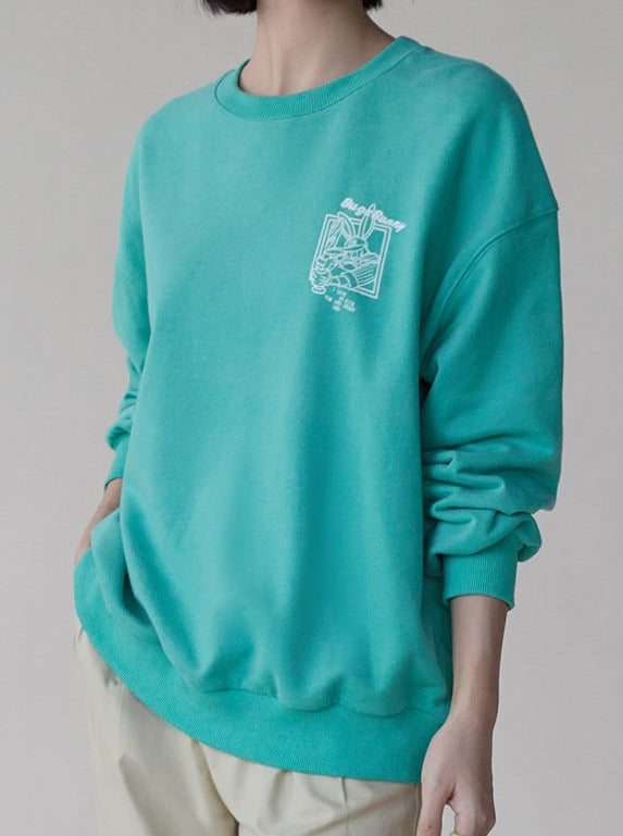 Damenpullover in Türkis, lässiger Stil, mit weißem Grafikdruck auf der Brust. Perfekt für Freizeitmode und trendige Outfits.