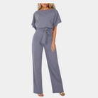 Stijlvolle dames jumpsuit in grijsblauw met korte mouwen en strikceintuur, perfect voor casual en formele gelegenheden. Comfortabele pasvorm.