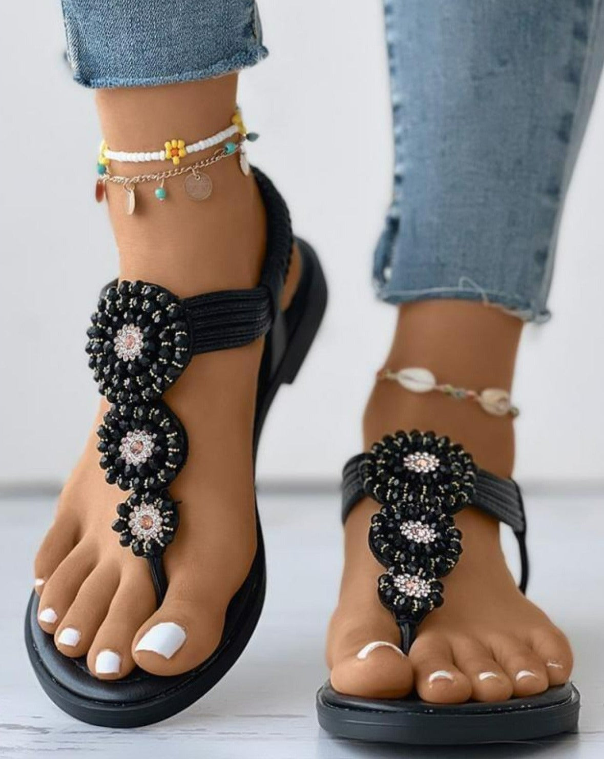 Schwarze Sandalen mit Perlenverzierung, ideal für Sommermode. Perfekt kombiniert mit Jeans und Fußkettchen. Bequeme und stilvolle Damen-Schuhe.