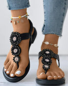 Schwarze Sandalen mit Perlenverzierung, ideal für Sommermode. Perfekt kombiniert mit Jeans und Fußkettchen. Bequeme und stilvolle Damen-Schuhe.