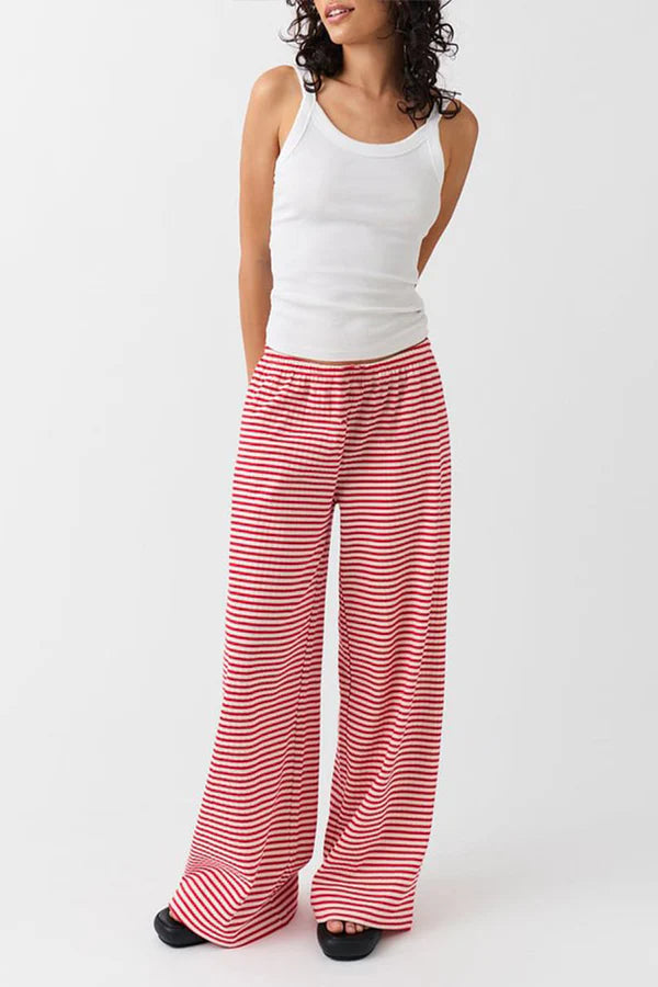 Frau in weißem Tanktop und rot-weiß gestreifter Hose. Modetrend, bequeme Damenbekleidung, lässiger Look, Sommeroutfit, Streifenmuster.