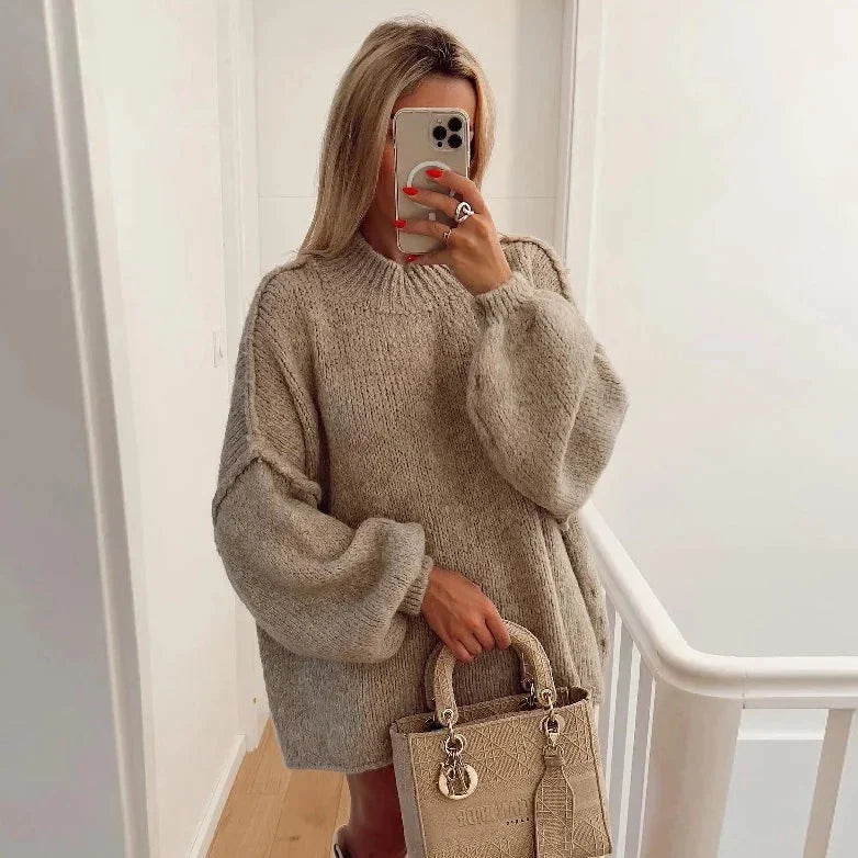 Frau in beigem Oversize-Pullover, hält Designer-Handtasche. Modetrend, Herbstmode, Strickpullover, Damenmode, stilvoll, elegant.