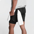 Mann in schwarzer Sporthose mit weißem Handtuch, Fitnessbekleidung, Rückansicht.