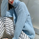 Damenmode: Hellblauer Strickpullover mit Zopfmuster, kombiniert mit gestreifter Hose. Stilvoller Look für Herbst und Winter.