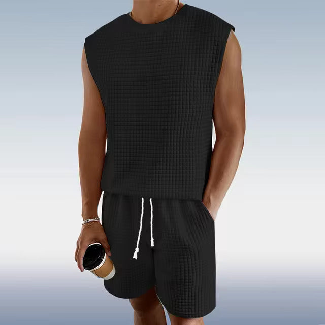 Mann in schwarzem ärmellosen Sommer-Set mit Shorts, hält Kaffeebecher, Freizeitmode.