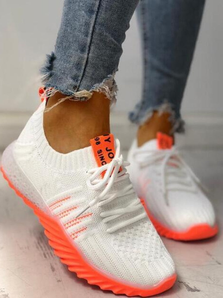 Weiße Sneaker mit neonorangen Akzenten, gestricktes Obermaterial, Damenmode, Freizeitschuhe.