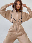 Damen-Jumpsuit in Beige mit Kapuze und schwarzen Reißverschlüssen. Modischer Einteiler, ideal für Freizeit und Streetwear. Bequem und stilvoll.