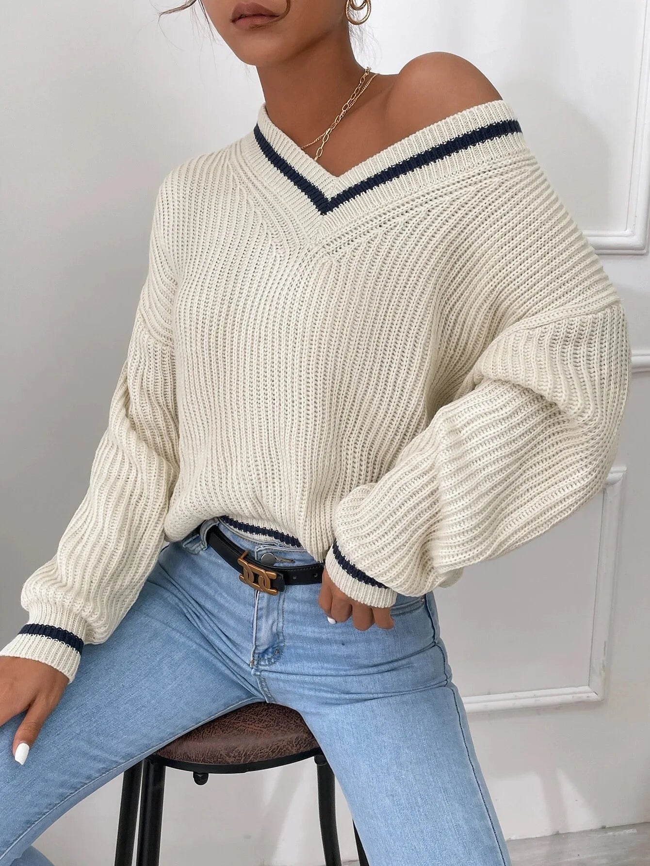 Damenpullover in Creme mit V-Ausschnitt, lässig gestrickt, kombiniert mit hellblauer Jeans. Modetrend, Herbstmode, bequeme Damenbekleidung.