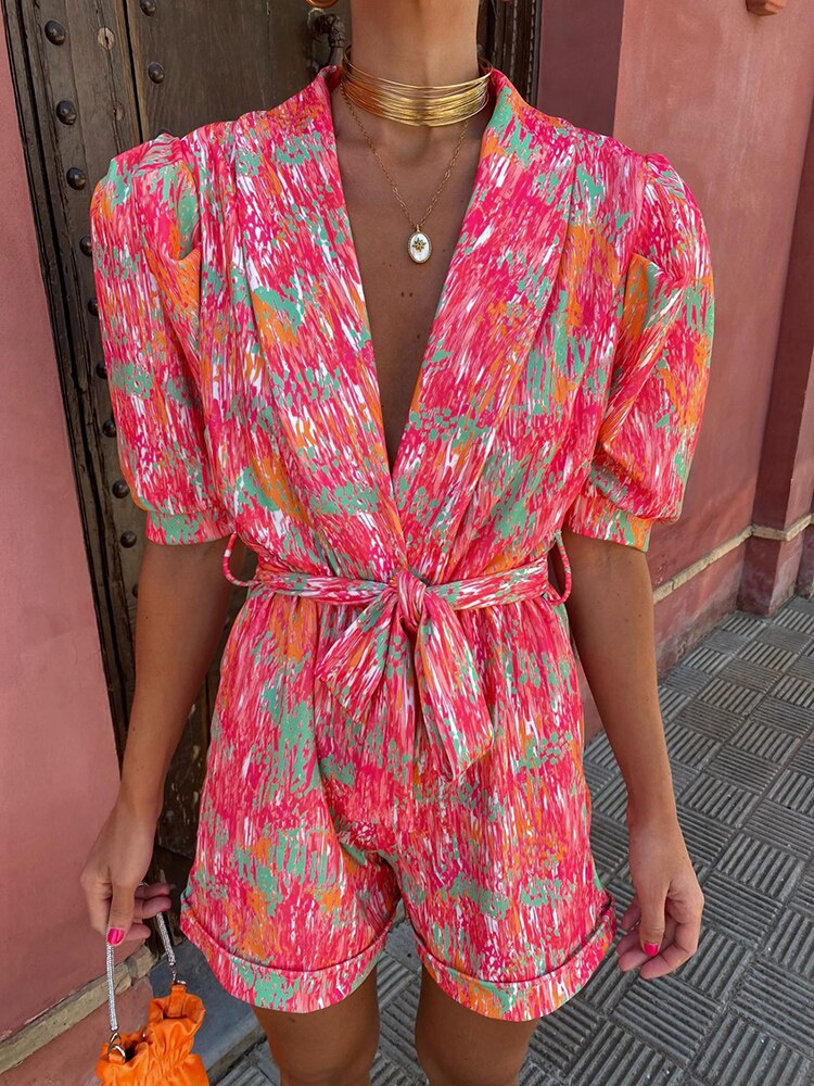 Farbintensiver Jumpsuit mit abstraktem Muster, Puffärmeln und Taillengürtel. Perfekt für Sommermode, Damenbekleidung, trendige Outfits.