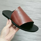 Braune Ledersandale, minimalistisches Design, schwarze Sohle, handgehalten, modisch, bequem.
