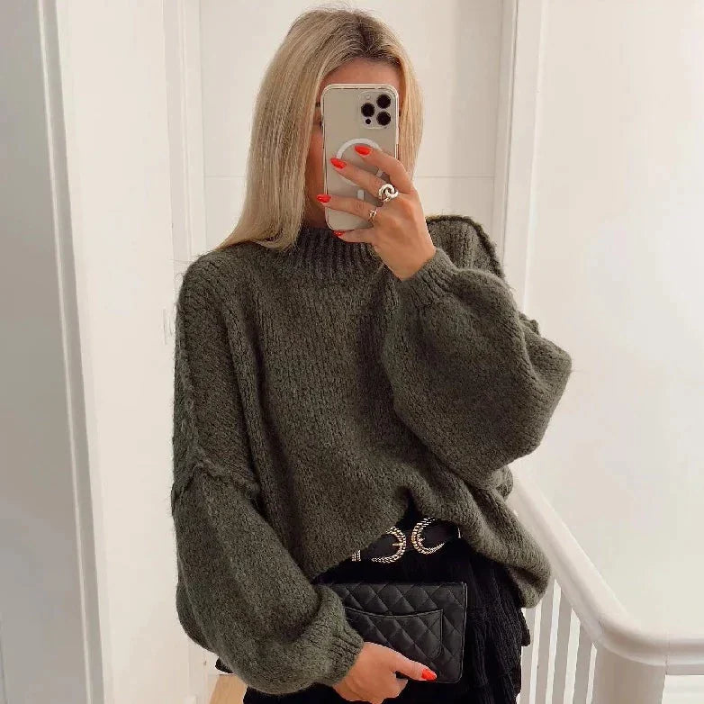 Frau in grünem Strickpullover, hält Smartphone, trägt schwarze Tasche. Modetrend, Herbstmode, Damenbekleidung, stilvoller Look.