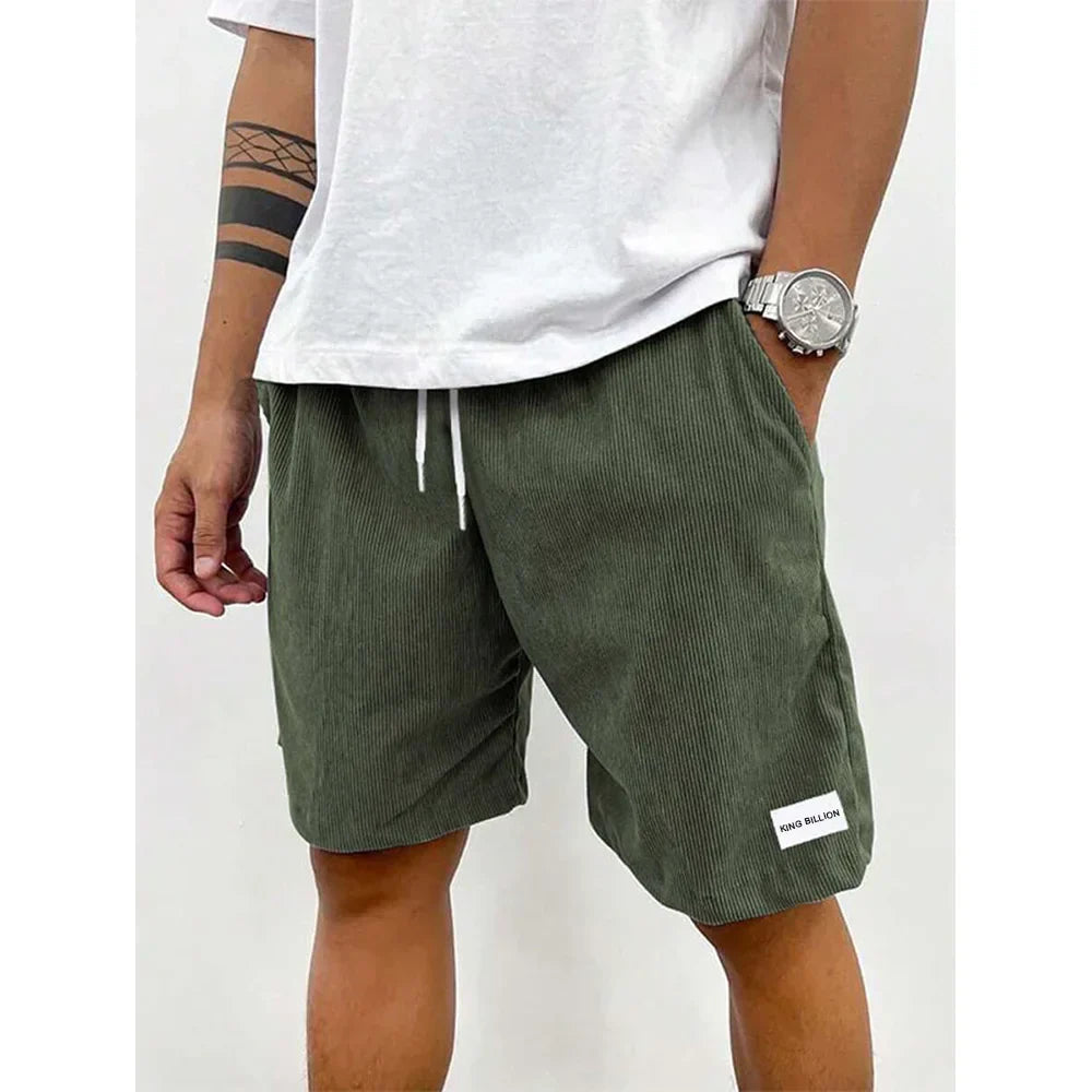Mann trägt olivgrüne Cord-Shorts, weißes T-Shirt, Armbanduhr, lässiger Sommerlook.