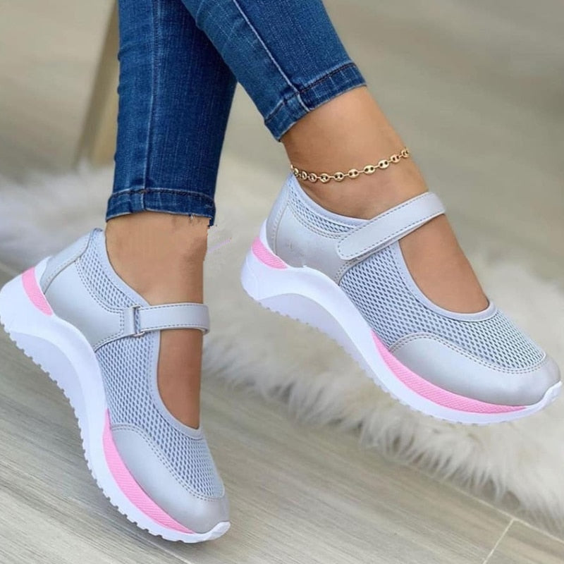 Damen-Sneaker in Grau mit Klettverschluss, atmungsaktivem Mesh-Obermaterial und rosa Akzenten. Bequeme Freizeitschuhe für Alltag und Sport.