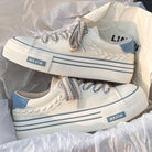Weiße Leinenschuhe mit blauen Akzenten, dicker Sohle und geflochtenen Details. Trendige Sneaker, ideal für Casual-Outfits und Streetwear.
