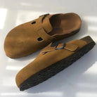 Braune Birkenstock Boston Clogs aus Wildleder mit verstellbarer Schnalle und rutschfester Sohle. Bequeme Schuhe für Damen und Herren.