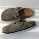Graue Birkenstock-Clogs aus Wildleder mit verstellbarer Schnalle und ergonomischem Fußbett. Bequeme Schuhe für Damen und Herren.