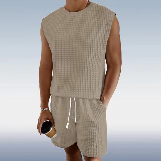 Mann in beige ärmellosem Waffel-Set, hält Kaffeebecher, Freizeitmode, Sommeroutfit.