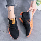 Schwarze Sneaker mit orangefarbener Sohle, atmungsaktives Mesh, sportlich, modern, Damenmode.