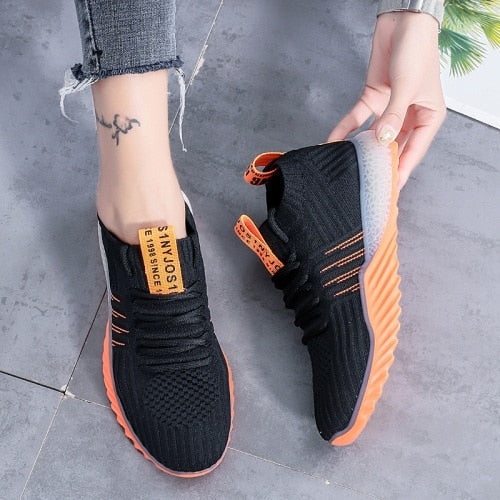 Schwarze Sneaker mit orangefarbener Sohle, atmungsaktives Mesh, sportlich, modern, Damenmode.