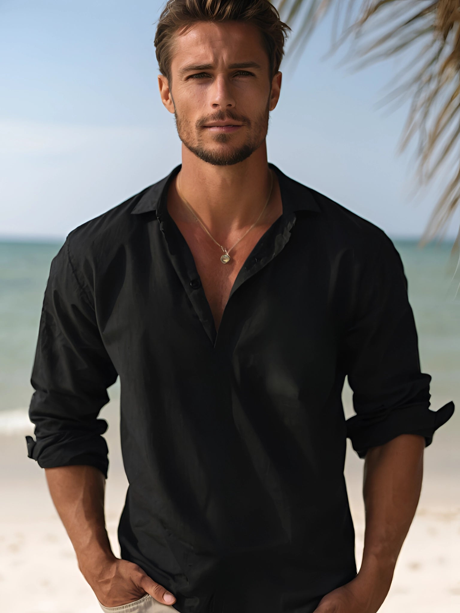 Mann in schwarzem Seidenhemd am Strand, Tavendia Luxusmode, elegantes Herrenhemd.